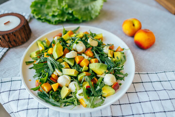 fresh salad with avocado mozzarella peach and arugula leaves served on plate. Healthy food, colorful ingredients concept, nutrition cooking wellness