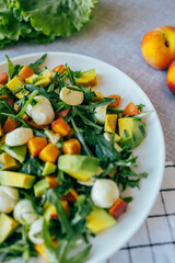 fresh salad with avocado mozzarella peach and arugula leaves served on plate. Healthy food, colorful ingredients concept, nutrition cooking wellness