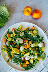 fresh salad with avocado mozzarella peach and arugula leaves served on plate. Healthy food, colorful ingredients concept, nutrition cooking wellness