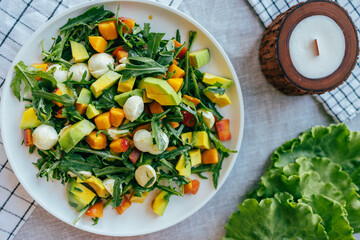 fresh salad with avocado mozzarella peach and arugula leaves served on plate. Healthy food, colorful ingredients concept, nutrition cooking wellness
