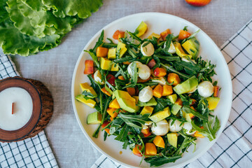 fresh salad with avocado mozzarella peach and arugula leaves served on plate. Healthy food, colorful ingredients concept, nutrition cooking wellness