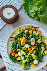 fresh salad with avocado mozzarella peach and arugula leaves served on plate. Healthy food, colorful ingredients concept, nutrition cooking wellness