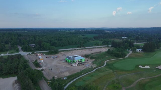 Drone aerial shot showing Golf Canada headquarters under construction at TPC Toronto Osprey Valley, with green walls, surrounding roads, golf course and forest.