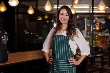 Smiling barista woman serving coffee behind counter at café, with espresso machine
