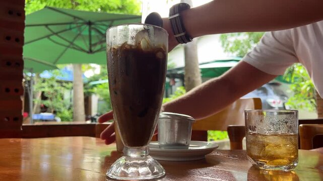 Barista mixing milk into a cup of ice coffee, mix Vietnamese coffee with condensed milk