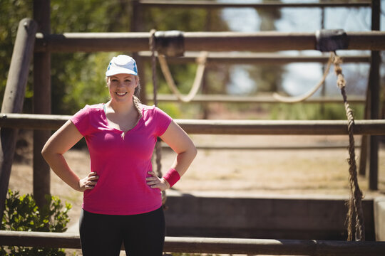 Fototapeta Wooden beams are standing with hanging ropes in obstacle course area under sunny sky, copy space