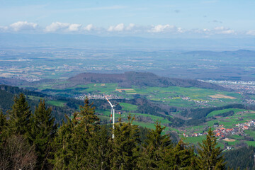 Breathtaking panoramic view of green valleys and hills showing wind turbines against a clear blue sky in the serene daytime landscape of the countryside
