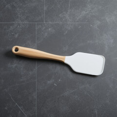 White silicone spatula with wooden handle on dark textured background