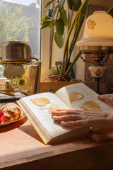 vintage kitchen interior, kitchen with antiques, hands on a book, book with herbarium, autumn mood
