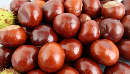 Fototapeta premium Close-up view of a collection of glossy, reddish-brown horse chestnuts, showcasing their smooth surfaces and vibrant hue.