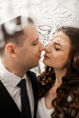 Closeup of happy couple having photoshoot outdoors, kissing. Young groom and bride getting married, smiling, enjoying, having photoshoot. Concept of happiness and family relations.