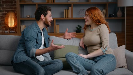 Caucasian happy smiling couple talking on couch at home emotional husband wife communicate man...