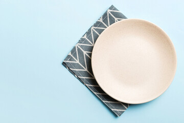 Top view on colored background empty round white plate on tablecloth for food. Empty dish on napkin...
