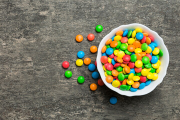 Multicolored candies in a bowl on a colored background. birthday and holiday concept. Top view with copy space