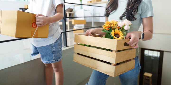 Home activity. A mother and daughter carrying wooden boxes filled with flowers, creating a warm atmosphere. - Powered by Adobe