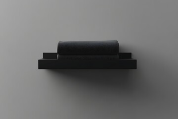 Sleek black floating shelf with rolled towel, minimal design on gray wall