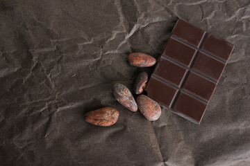 Cocoa beans. Chocolate bar. Bean-to-bar chocolate production. Brown crumpled wrapping paper. Copy space. Shallow Depth of Field.