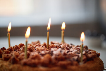 Chocolate cake with five lit candles standing on top, celebrating birthday or special occasion,...
