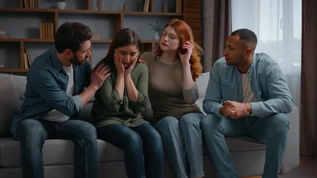 Four multiracial people home party frustrated woman friends supporting calming on couch together upset girl holding head talking problem breakup diverse men women buddies consoling psychological help