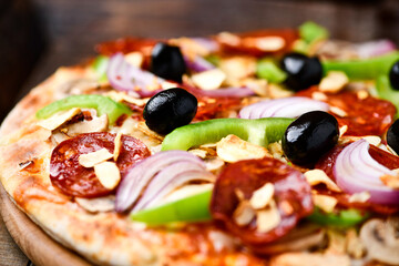 Pizza with chorizo ​​sausage, mozzarella cheese, green pepper and black olives. Rustic wooden background. Soft focus.	