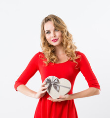 Cute blonde woman in red dress with gift in hands looking at camera and smiling isolated on white background.