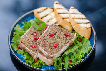 A delectable display of gourmet pate served on lettuce leaves, accompanied by slices of fresh baguette, and garnished with vibrant pomegranate seeds.