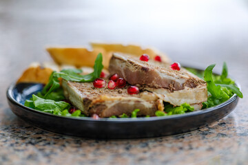 A delectable display of gourmet pate served on lettuce leaves, accompanied by slices of fresh baguette, and garnished with vibrant pomegranate seeds.