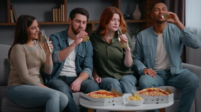 Happy multiethnic four friends at home party cheers clinking bottles multiracial people men women drinking alcohol beer cider drinks enjoy fun pizza delivery buddies spending weekend together friendly