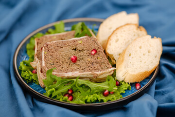 A delectable display of gourmet pate served on lettuce leaves, accompanied by slices of fresh baguette, and garnished with vibrant pomegranate seeds.