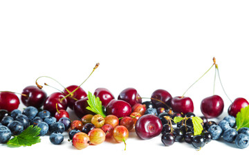 Ripe fresh berries of blueberry, blackcurrant, cherry and gooseberry with leaves isolated on white.