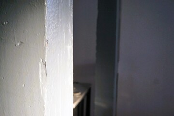 Innenausstattung von altem Fachwerkhaus mit weißen und grauen Holzbalken vor hellgrauer Wand am abend im Winter