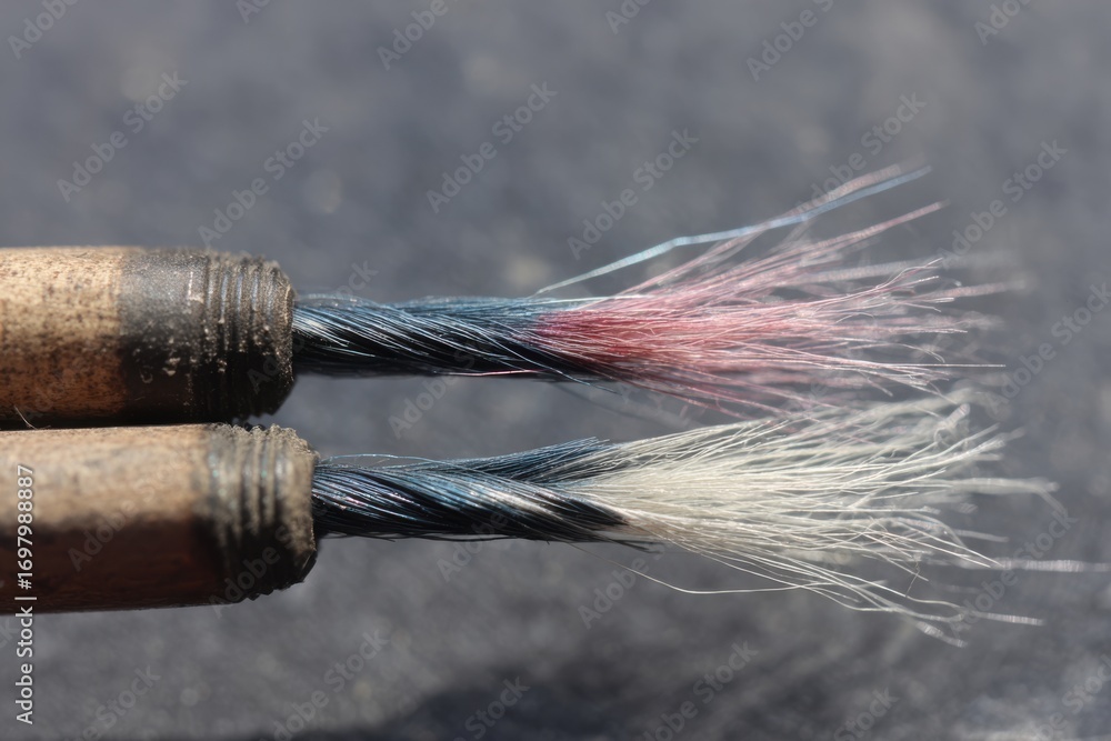 Poster close-up of braids with different color fibers showing texture and wear on a black surface capturing