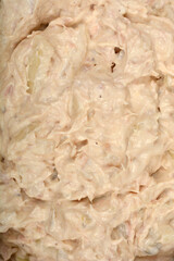 A textured close-up shows a creamy tuna and cream cheese spread from a top-down view