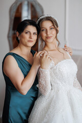 Mother and daughter pose together in elegant wedding attire before ceremony