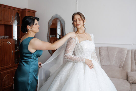 Bridal preparation in elegant setting as mother helps bride with wedding gown