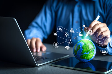 Businessman holding a stylus pen, poking at a globe and showing icons with the concepts of green...