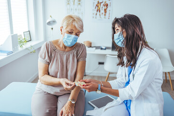 Doctor Consulting an Elderly Woman in a Medical Office Wearing Face Masks