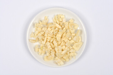 An overhead view of a small white plate with a pile of freshly chopped garlic