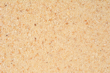 An overhead, detailed macro shot of a texture made of small, irregularly shaped pieces of breadcrumbs