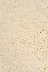 A macro shot shows the fine, clumpy texture of white flour, scattered unevenly across a surface