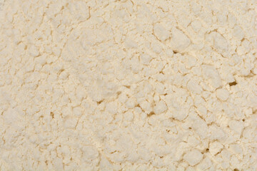 A macro shot shows the fine, clumpy texture of white flour, scattered unevenly across a surface
