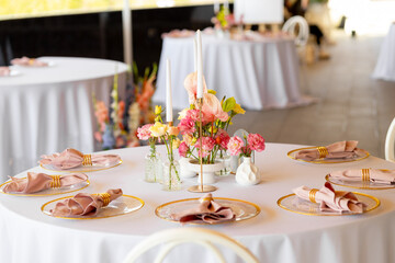 Table decor in a restaurant with beautiful vases of pink anthurium flowers, roses and carnations. Celebration, wedding