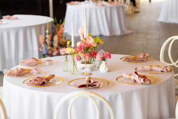 Table decor in a restaurant with beautiful vases of pink anthurium flowers, roses and carnations. Celebration, wedding
