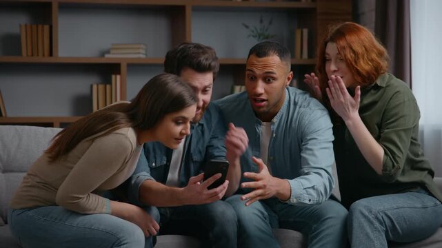 Four multiracial friends at home party with mobile phone winning casino betting waiting result watching online sport game broadcasts happy yelling celebrate internet victory diversity people triumph