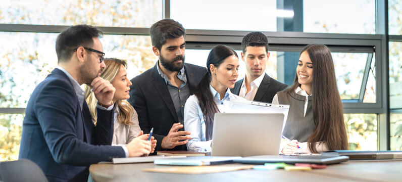 roup of business partners analyzing paper data with female CEO leader in office