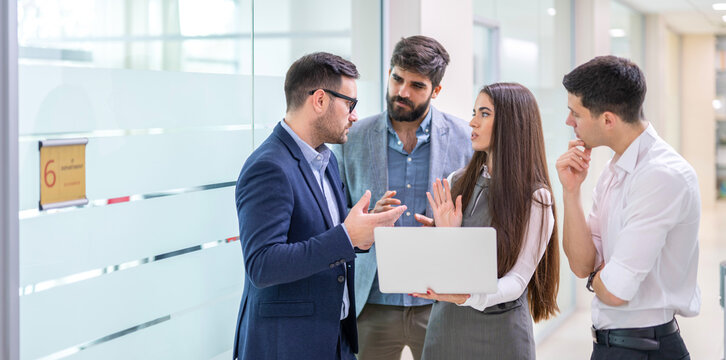 Business people standing in office hallway discussing report during impromptu meeting