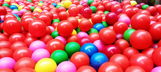 A top view image of a vibrant and colorful background of plastic balls in various colors.