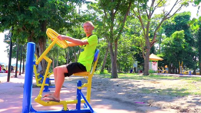 Man jokes around on exercise machine equipment for sports Thailand.
