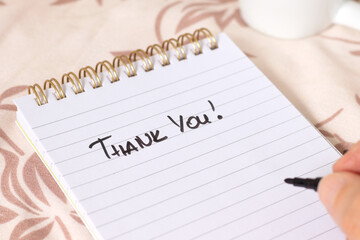 Obraz premium Hand writing Thank You quote in notebook with cup of coffee. Close-up. Christian thanksgiving and gratitude concept.