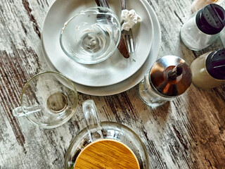 Messy gathering of dirty dishes on a rustic wooden table after a meal at a cozy cafe